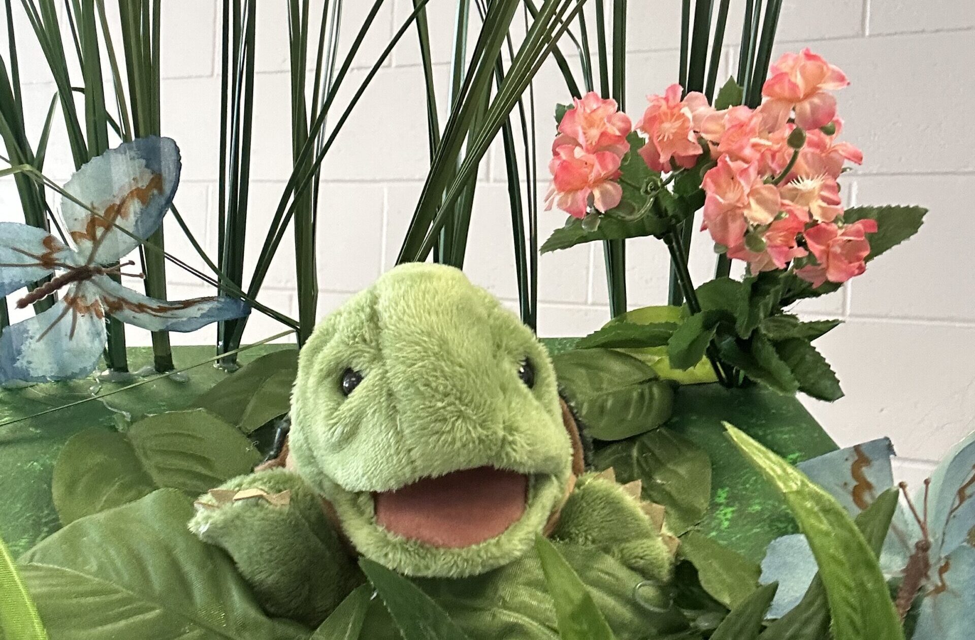 Une tortue en peluche dans des plantes.