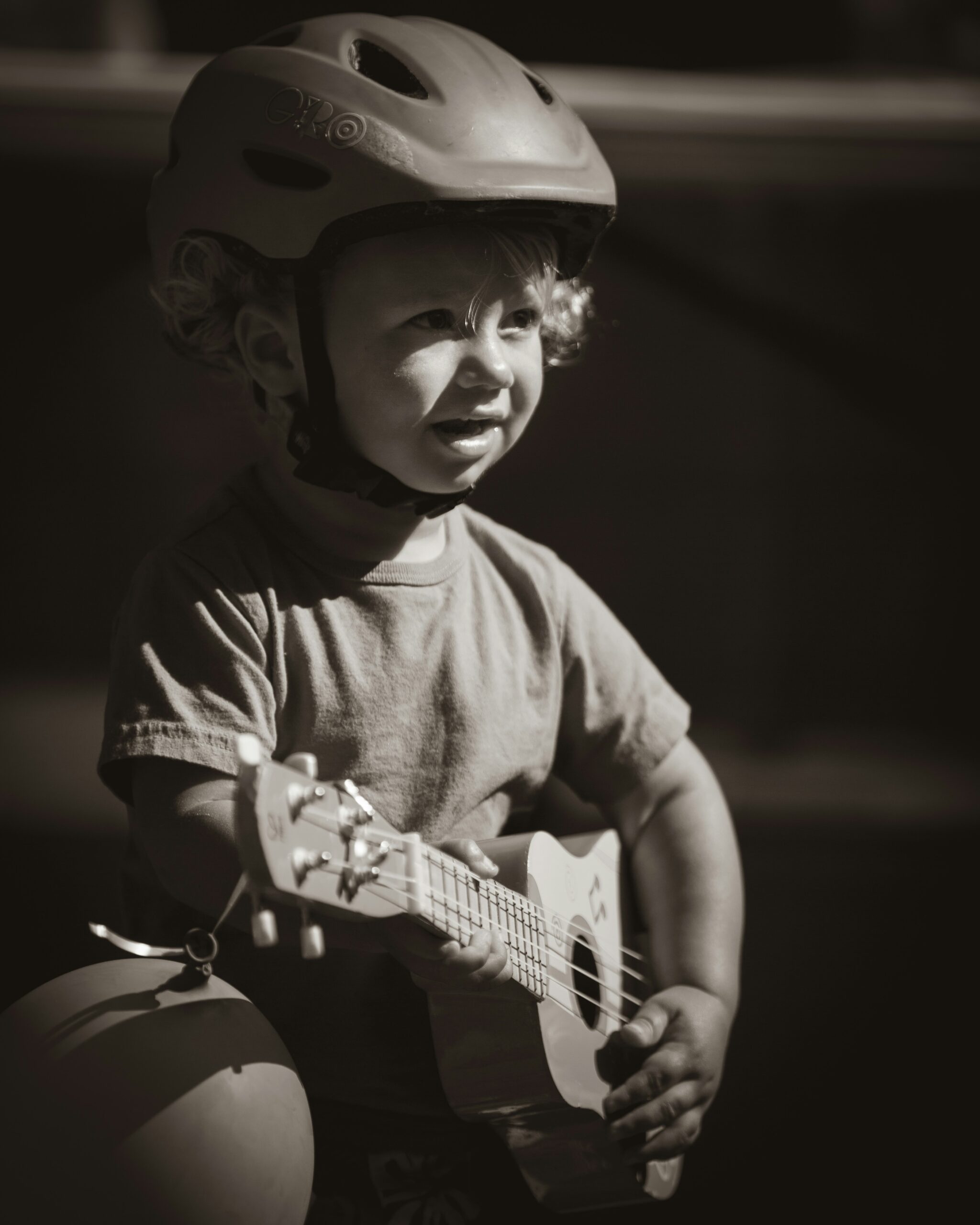 Photo en noir et blanc d'un petit garçon qui joue une petite guitare.